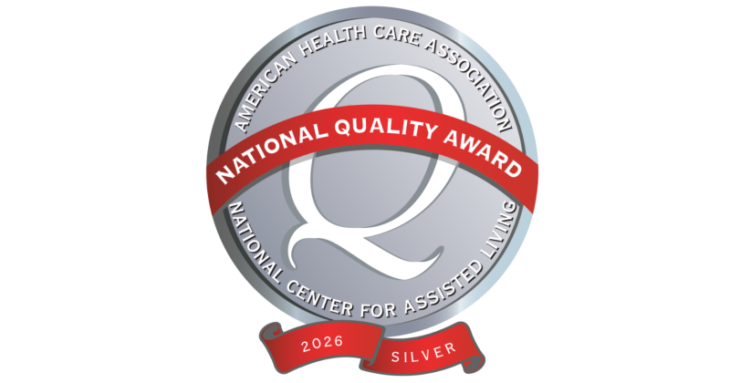 A circular certification badge with a silver background, featuring a large 